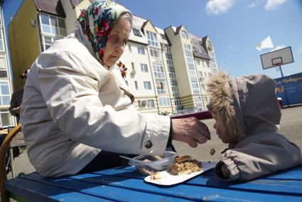 Бабушка-ветеран кормит внука во время прогулки на аллее. Екатеринбург