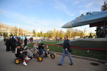 Молодые люди катаются на веломобиле во время выставки образцов российского вооружения на ВДНХ в Москве.