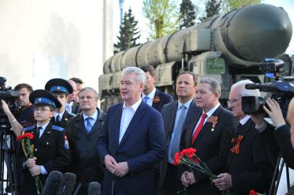 Мэр Москвы Сергей Собянин (в центре) и руководитель Федерального космического агентства (Роскосмос) Игорь Комаров (третий справа) во время общения с журналистами после осмотра выставки образцов российского вооружения у павильона `Космос` на ВДНХ в Москве.