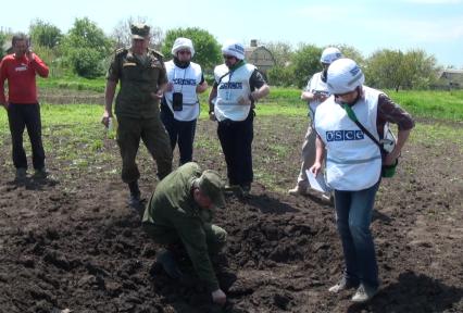 Украина. Донецкая область. с.Саханка. Представитель совместной российско-украинской группы по координации прекращения огня Александр Ленцов (второй слева) и представители ОБСЕ осматривают воронку.