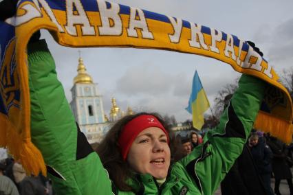 Киев. Акция сторонников Евроинтеграции Украины на Михайловской площади. Женщина держит шарф в цветах украинского флага. Надпись на шарфе `Слава Украине`.