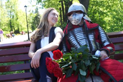 Выпускница школы празднующая последний звонок, фотографируется с парнем в рыцарских доспехах, пришедшем на свидание. Екатеринбург