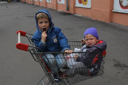 Москва. Дети сидят в магазинной тележке.