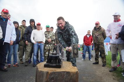 Полномочный представитель президента в УрФО Игорь Холманских (в центре) чеканит кувалдой памятную монетку на Демидовской пристани на реке Чусовая, в деревне Усть-Утка. Свердловская область