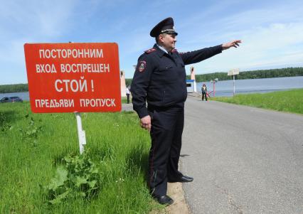 Московская область. Сотрудники полиции отрабатывают задержание преступников на Учинском (Акуловском) водохранилище. Полицейский стоит у таблички `Посторонним вход воспрещен. Стой! Предъяви пропуск`.