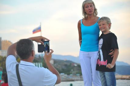 Алушта. Мужчина фотографирует женщину с ребенком на набережной.