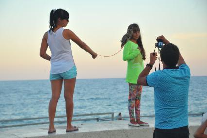 Алушта. Девочка фотографируется с филином на набережной.