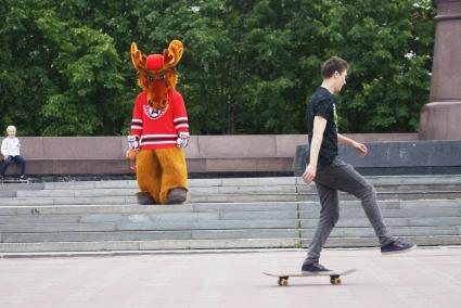 Символ ХК \"Автомобилист\" лось Автик наблюдает за парнем на скейтборде во время празднования Дня России. Екатеринбург
