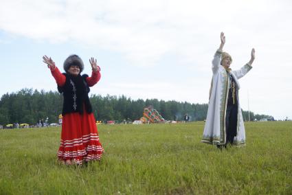 Мужчина и женщина в национальных Башкирских костюмах танцуют в поле, во время празднования Сабантуя. село Кадниово. Свердловская область