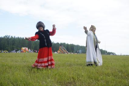 Мужчина и женщина в национальных Башкирских костюмах танцуют в поле, во время празднования Сабантуя. село Кадниово. Свердловская область