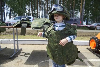 Военнослужащий одевает на ребенка бронежилет и армейскую каску с защитными очками, перед началом военно-спортивной игры \"Гонка героев\" на полигоне 32-го военного городка. Екатеринбург