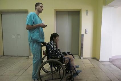 Тула. Тульская областная больница. Санитар везет женщину на инвалидной коляске.
