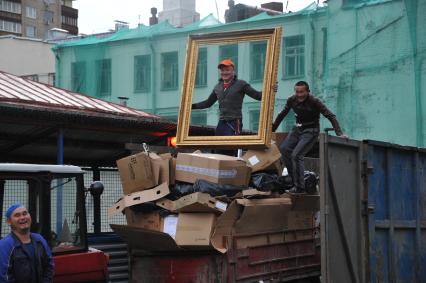 Москва. Гастарбайтеры сгружают мусор в контейнер.