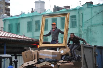 Москва. Гастарбайтеры сгружают мусор в контейнер.