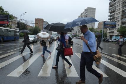 Проливной дождь в Москве. Люди переходят проезжую часть по пешеходному переходу.