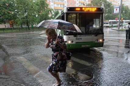 Проливной дождь в Москве. Люди переходят проезжую часть по пешеходному переходу.