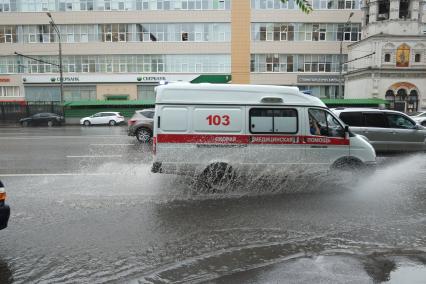 Проливной дождь в Москве. Машина Скорой помощи едет по дороге.