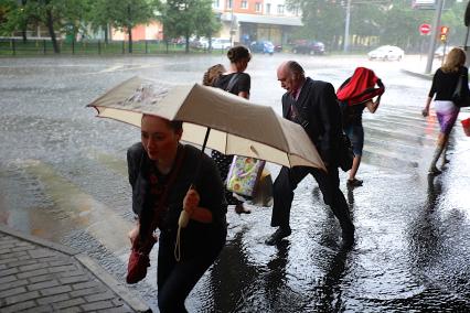 Проливной дождь в Москве. Люди переходят проезжую часть по пешеходному переходу.