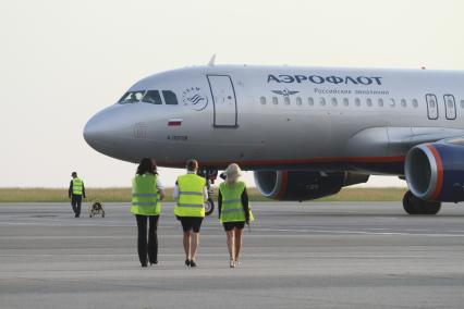 Барнаул. Персонал барнаульского аэропорта идет к самолету Airbus A320 российской авиакомпании `Аэрофлот`.