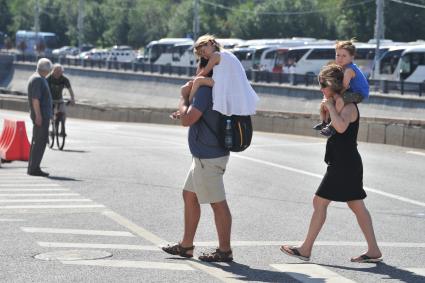 Москва. Родители с детьми на плечах переходят дорогу.