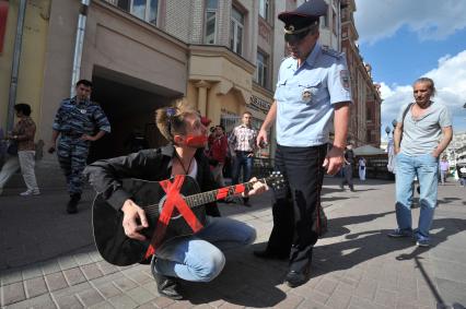 Москва. На Старом Арбате прошла акция протеста уличных музыкантов.
Артист заклеил гитару и рот скотчем в знак несогласия с действиями полиции.