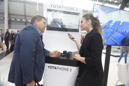 посетитель у стенда компании \"Yota Devices\" презентующей телефон Yotaphone 2. Выставка \"Иннопром - 2015\" . Екатеринбург