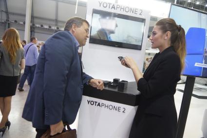 посетитель у стенда компании \"Yota Devices\" презентующей телефон Yotaphone 2. Выставка \"Иннопром - 2015\" . Екатеринбург