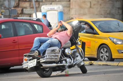 Москва. Мужчина лежит на мотоцикле на площади Белорусского вокзала.