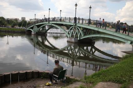 Москва. Мужчина ловит рыбу возле пешеходного моста в парке Царицыно.