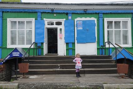 Маленькая девочка у входа в сельский магазин, зазывая покупателей. Свердловская область. Верхотурье