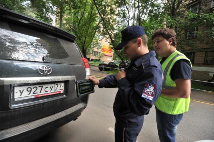 Москва. Контролер `Московского паркинга` снимает на портативный комплекс фото-видеофиксации номер автомобиля, стоящего в зоне платной парковки, с целью проверки оплаты места.