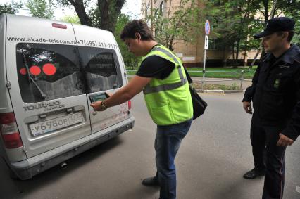 Москва. Контролер `Московского паркинга` снимает на портативный комплекс фото-видеофиксации номер автомобиля, стоящего в зоне платной парковки, с целью проверки оплаты места.