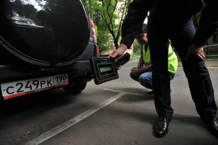 Москва. Контролер `Московского паркинга` снимает на портативный комплекс фото-видеофиксации номер автомобиля, стоящего в зоне платной парковки, с целью проверки оплаты места.