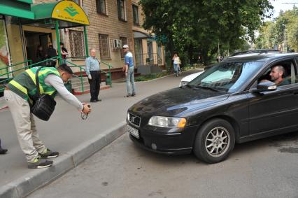 Москва. Контролер `Московского паркинга` снимает на портативный комплекс фото-видеофиксации номер автомобиля, стоящего в зоне платной парковки, с целью проверки оплаты места.