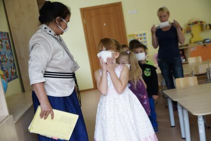 Воспитатель выводит детей в ватно-марлевых повязках, во время учебной эвакуации из детсого сада при пожаре. Екатеринбург