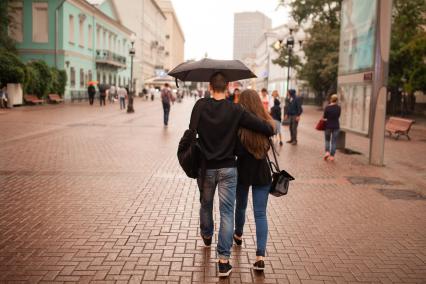 Москва. Молодая пара идет под зонтом по Старому Арбату.