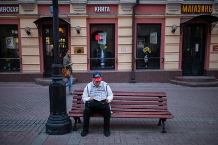 Москва. Пожилой мужчина отдыхает на скамейке на Старом Арбате.