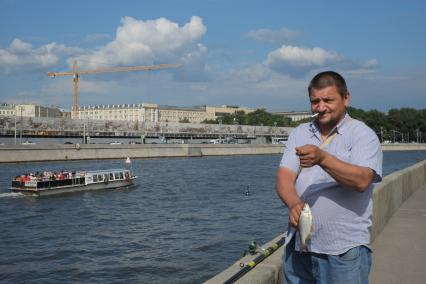 Москва. Мужчина рыбачит на набережной Москва-реке.