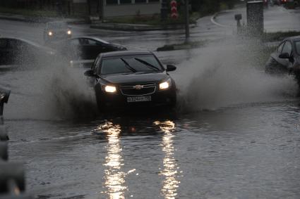 Ливень в Москве. Автомобили едут по лужам.