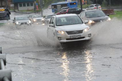 Ливень в Москве. Автомобили едут по лужам.