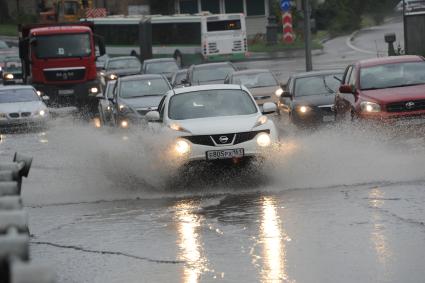 Ливень в Москве. Автомобили едут по лужам.