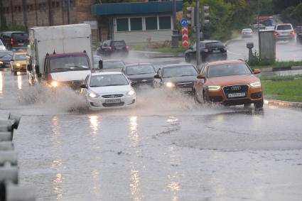 Ливень в Москве. Автомобили едут по лужам.