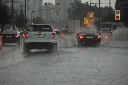 Ливень в Москве. Автомобили едут по лужам.