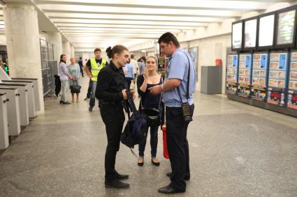 Москва. Контролер московского метрополитена проверяет проездные билеты у пассажиров у турникетов на станции `Пушкинская`.