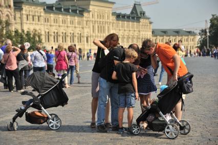 Москва. Люди смотрят фотографии, снятые на мобильный телефон на Красной площади.