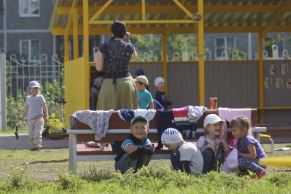 Дети прячутся от воспитателя за скамейкой,во время прогулки на детской площадке детского сада. Екатеринбург
