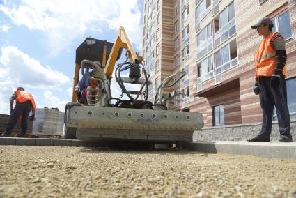 Рабочие укладывают брусчатку во дворе строящегося многоэтажного дома в районе \"Солнечный\". Екатеринбург