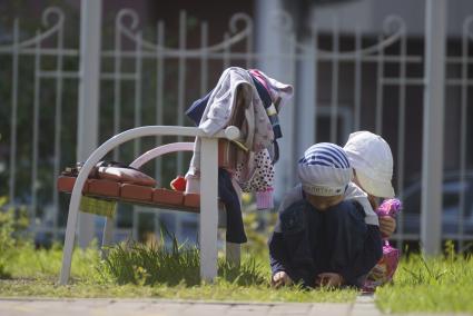 Дети прячутся от воспитателя за скамейкой,во время прогулки на детской площадке детского сада. Екатеринбург