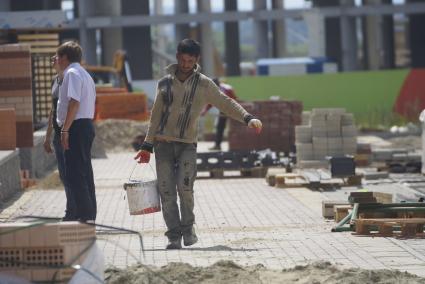 Рабочий несет ведро с цементом. Строительство многоэтажного дома в районе \"Солнечный\". Екатеринбург