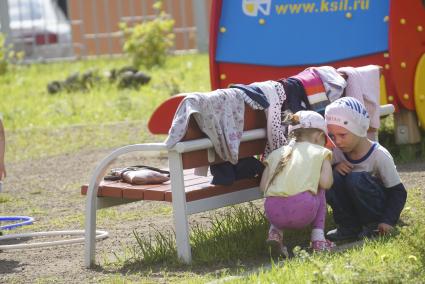 Дети прячутся от воспитателя за скамейкой,во время прогулки на детской площадке детского сада. Екатеринбург